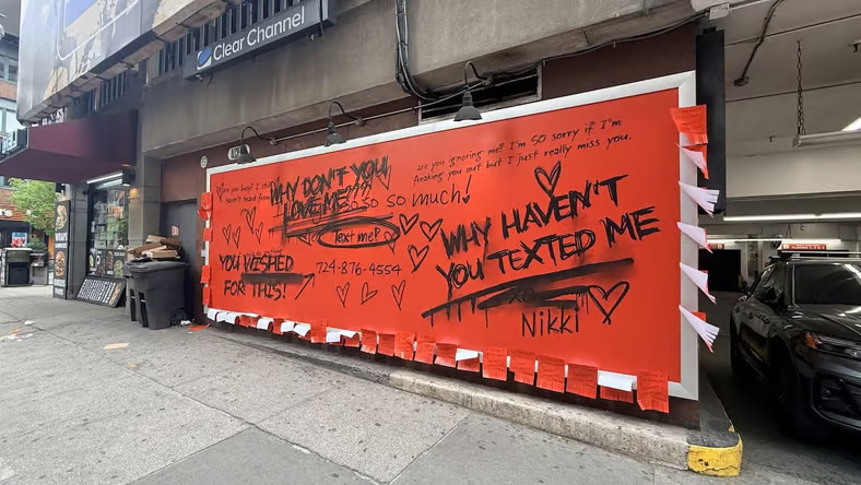 A red billboard covered in handwritten love notes